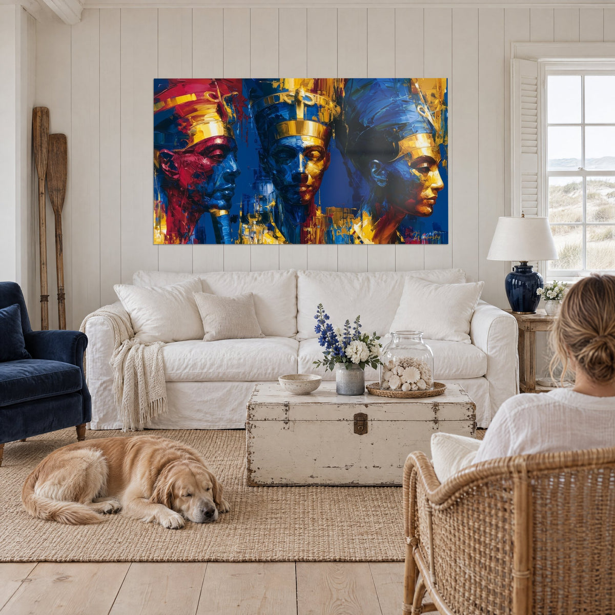 Wall art three pharaohs with gold headdresses, faces in red, blue and ochre, above a sofa in a bright living room