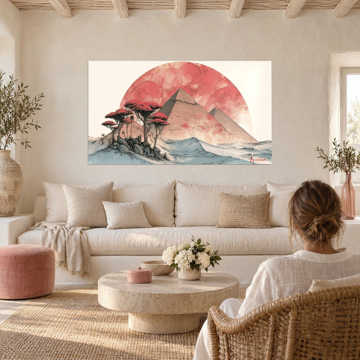 Wall art of beige pyramids under a large coral sun, red acacias in the foreground, hung above a sofa in a bright living room