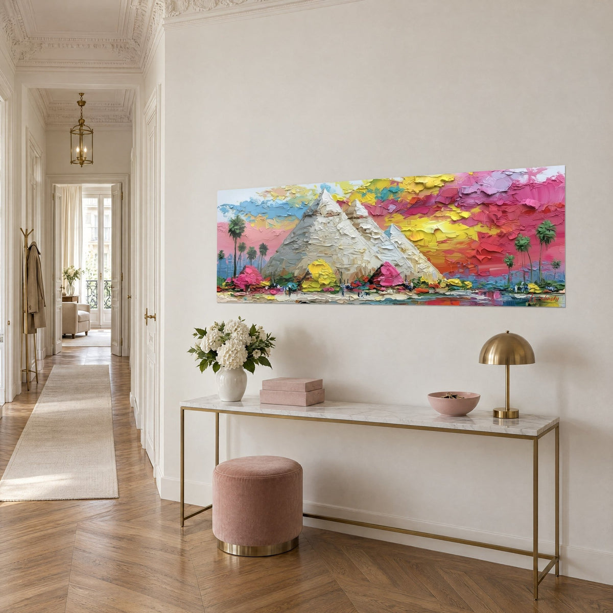 Quadro tre piramidi in pasta spessa crema e grigia, cielo rosa e giallo limone, visto di tre quarti su una console dorata