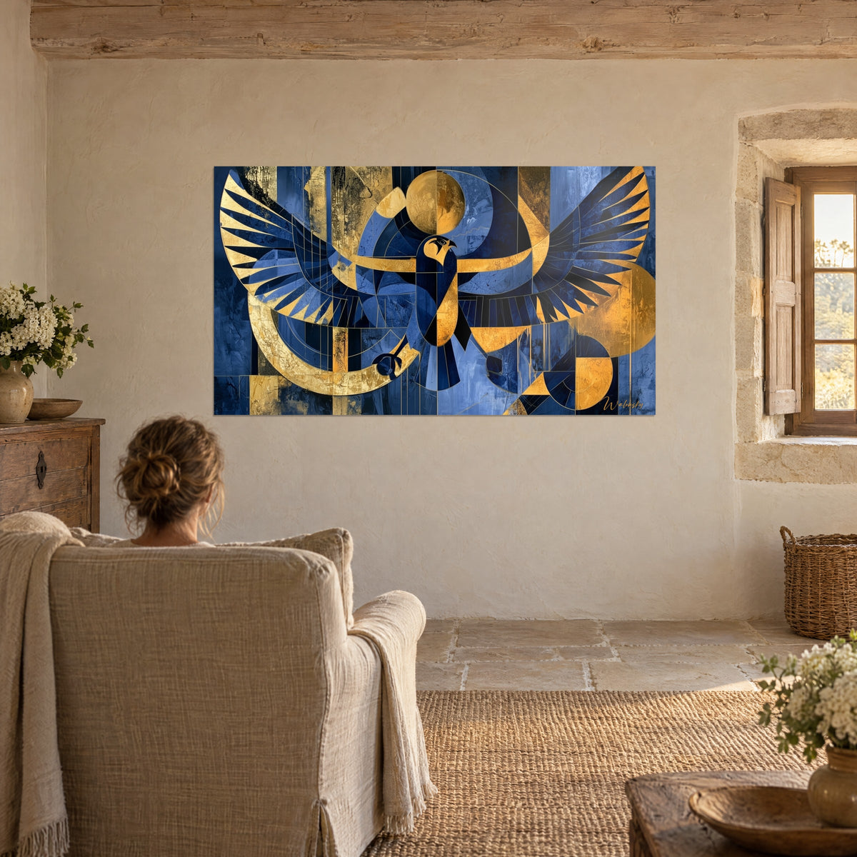 Wall art falcon in flight with navy feathers, crescent and gold disc, facing a beige armchair near a window
