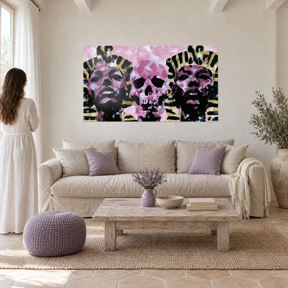 Tableau deux pharaons aux coiffes dorées et rayées de noir encadrant un crâne rose, au-dessus d'un canapé dans un salon lumineux