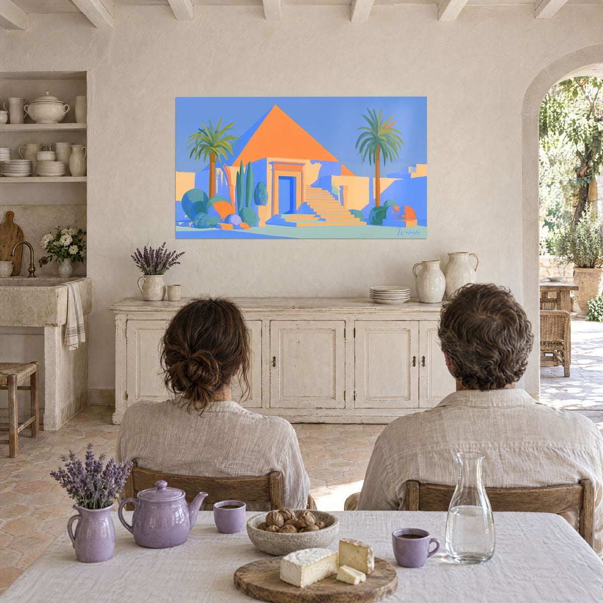 Wall art Egyptian oasis with sand-coloured walls, orange pyramid under a periwinkle sky, couple seen from behind seated at the kitchen table of the farmhouse