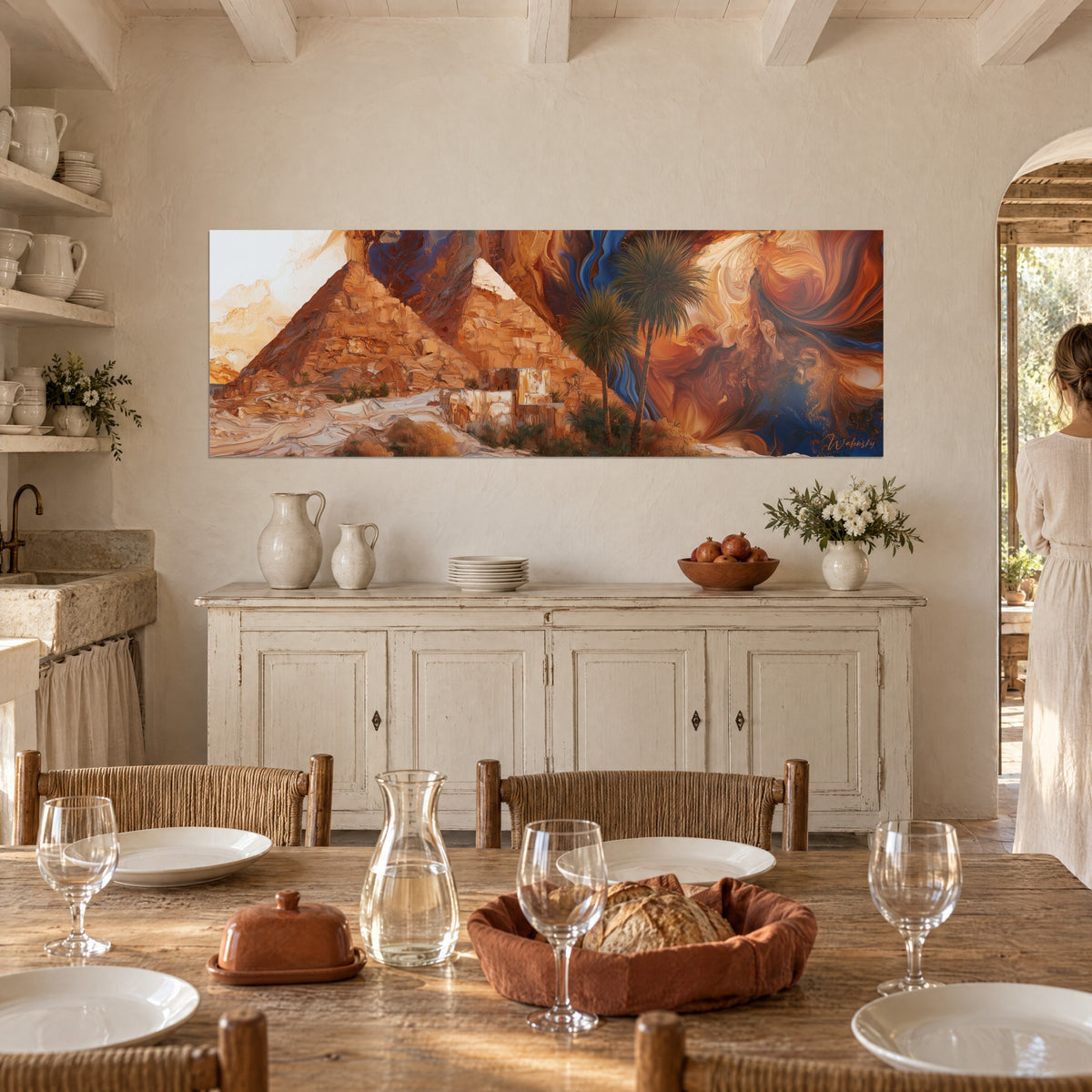 Wall art of golden stone peaks at the foot of two palm trees, rust and blue spirals, above a white sideboard, two silhouettes in the kitchen