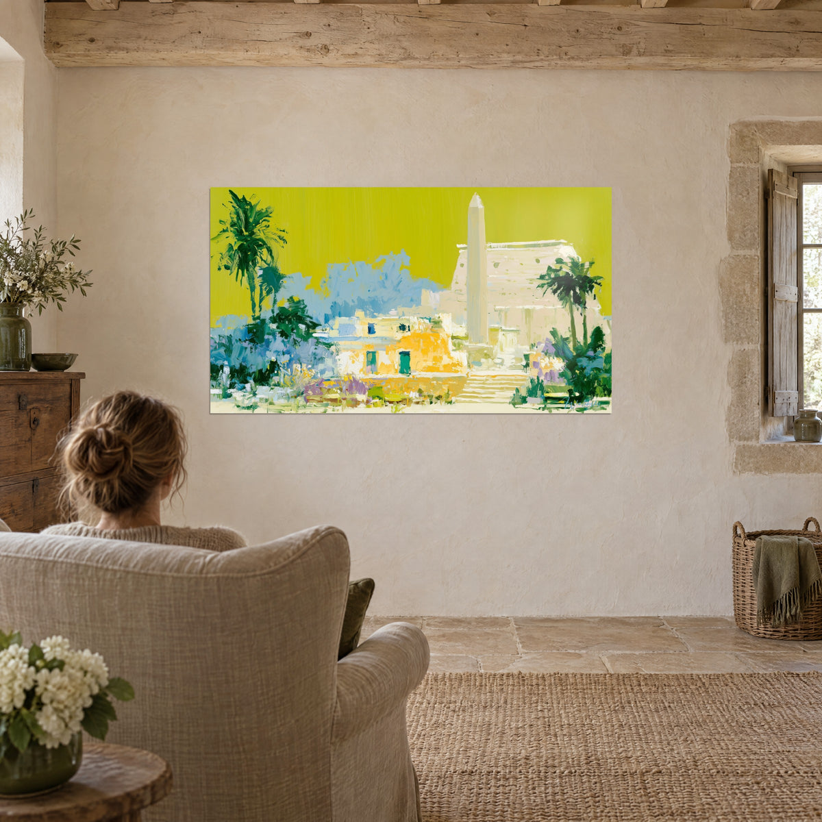 Cuadro de un paisaje de Luxor con pintura gruesa, amarillo chartreuse y azul cielo, con una mujer sentada de espaldas en un sillón de lino