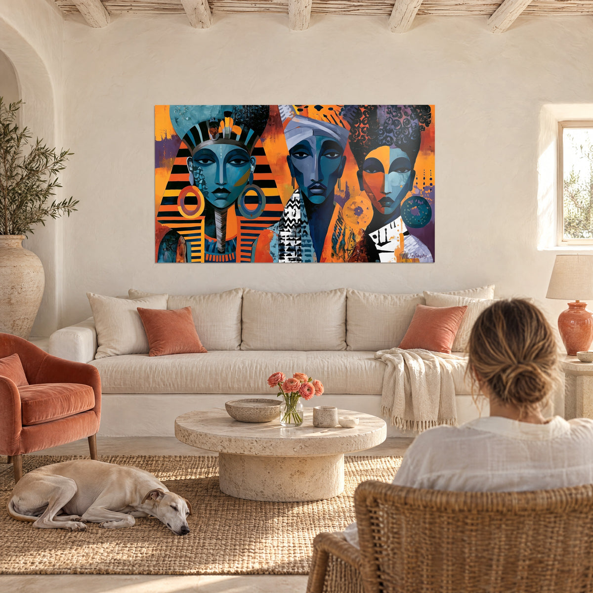 Schilderij met drie farao-gezichten in turquoise en oranje, gestreepte hoofddoek, grote ronde krullen, boven een bank in een lichte woonkamer
