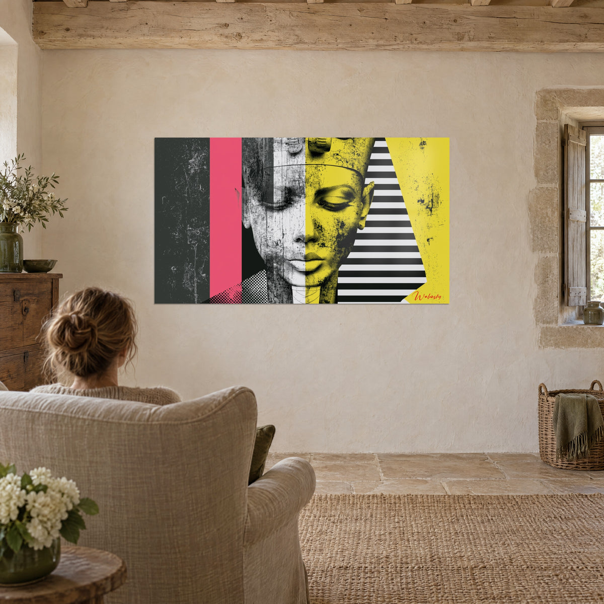 Cuadro perfil real egipcio en pop art, amarillo ácido, gris texturizado y rosa frambuesa, frente a un sillón de lino y un ramo blanco