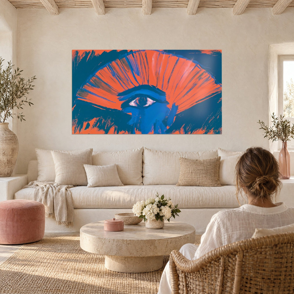 Wall art Eye of Horus in cobalt blue, opened over a fan of bright orange stripes, hung above a sofa in a bright living room