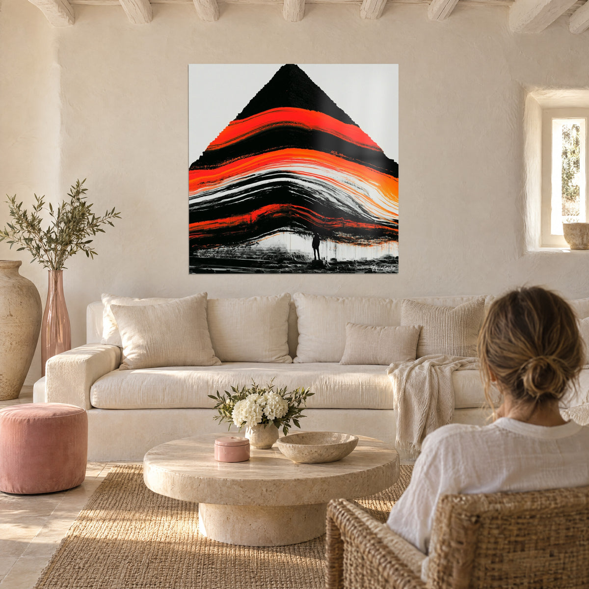 Tableau pyramide sombre striée de vagues rouge vif et orange, silhouette minuscule au pied, au-dessus d'un canapé dans un salon lumineux