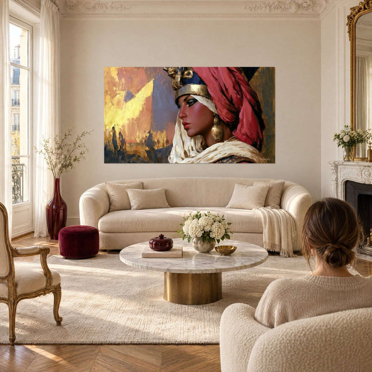 Schilderij Egyptische koningin met karmijnrode tulband, gouden hoofdtooi en okerkleurige lucht, van achteren gezien, boven een bank in een lichte woonkamer