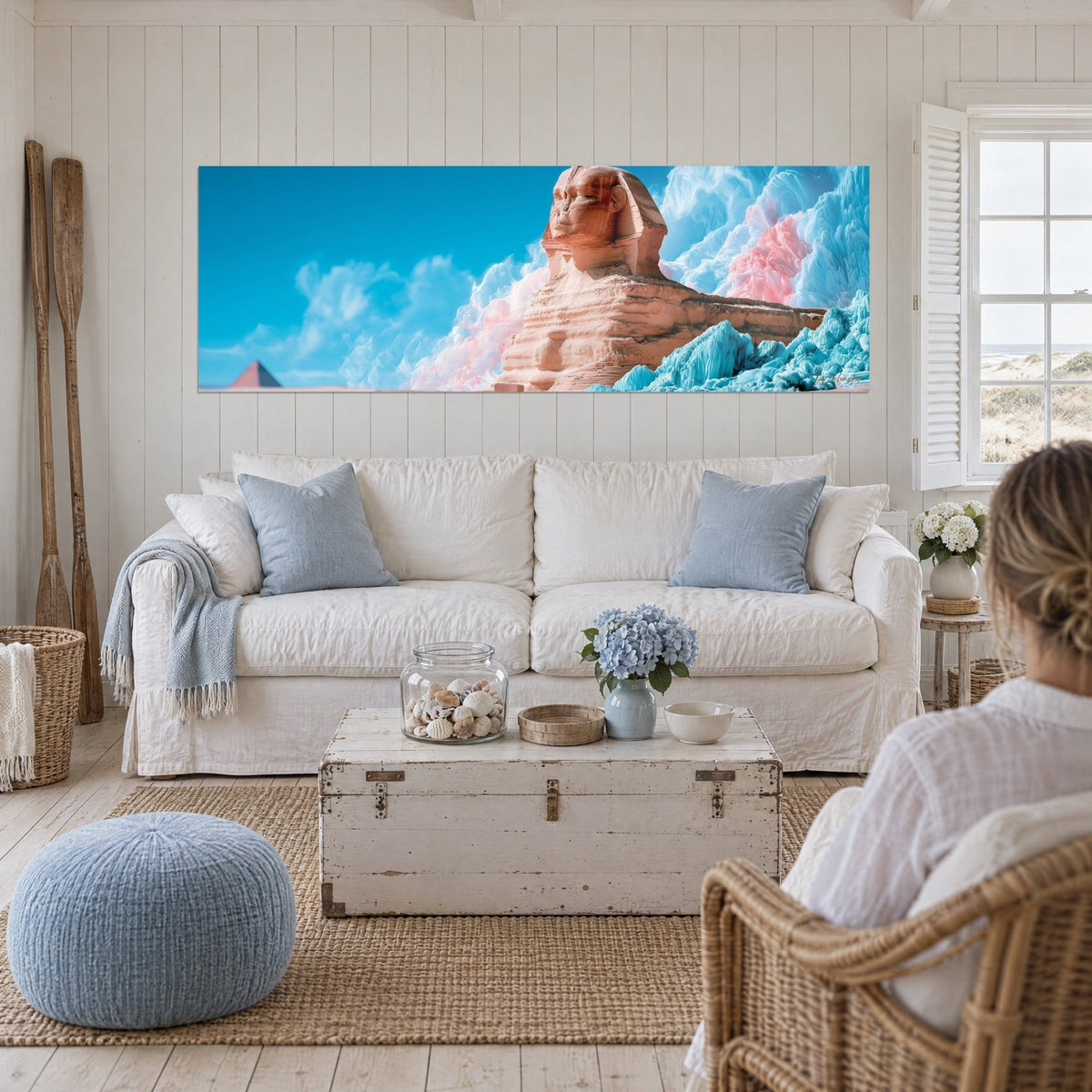 Gemälde Sphinx von Gizeh in Ockertönen vor azurblauem Himmel, blaue und rosa Eisflächen, zwei Personen von hinten, über einem Sofa in einem hellen Wohnzimmer