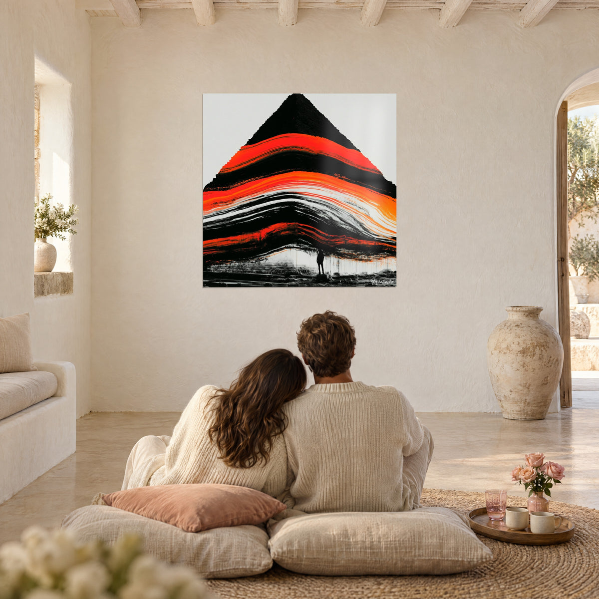 Tableau montagne noire ondulée de rubans vermillon et orange, fond blanc cassé, face à un couple de dos assis sur des coussins