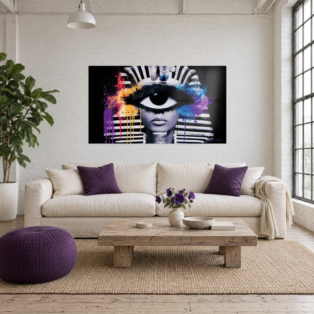 Cuadro faraón de ojo único, pañuelo rayado en blanco y negro, salpicaduras violetas y naranjas, sobre un sofá en un salón luminoso