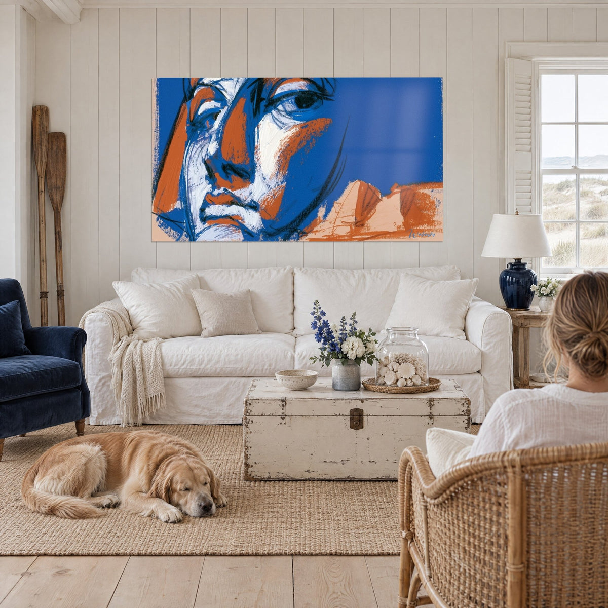 Quadro di volto severo dai tratti blu e terracotta, sopra un divano in un soggiorno luminoso