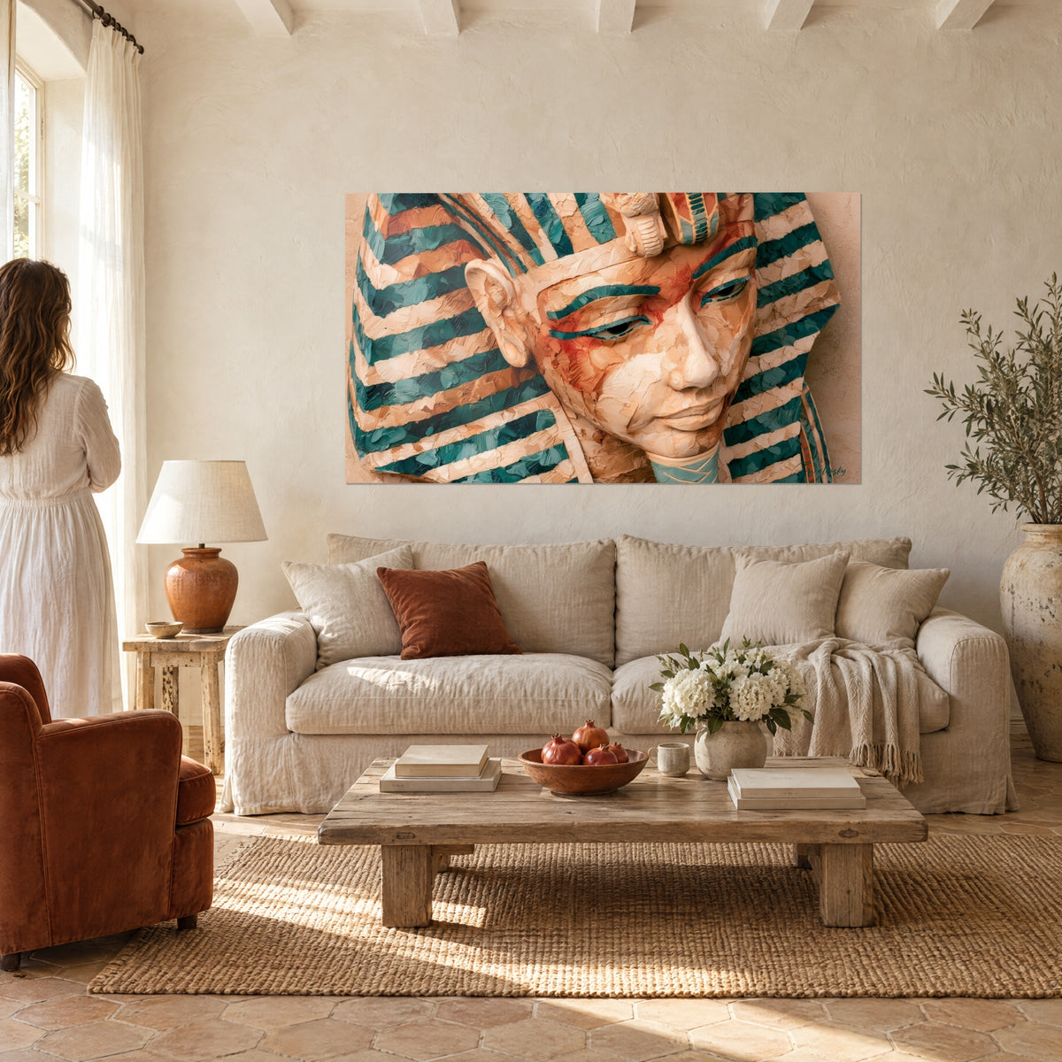Tableau pharaon au regard baissé, bandeau rayé turquoise et beige, paupières fardées de rouge, au-dessus d'un canapé dans un salon lumineux