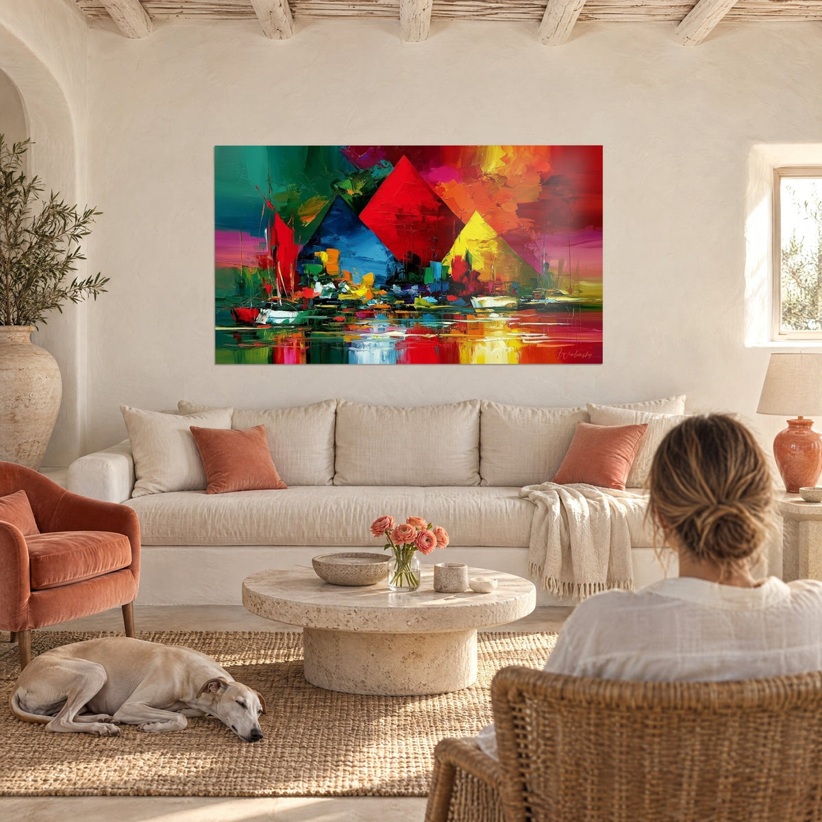 Quadro piramidi rosso vivo e blu cobalto su un porto dai riflessi gialli, viste di spalle, sopra un divano in un soggiorno luminoso