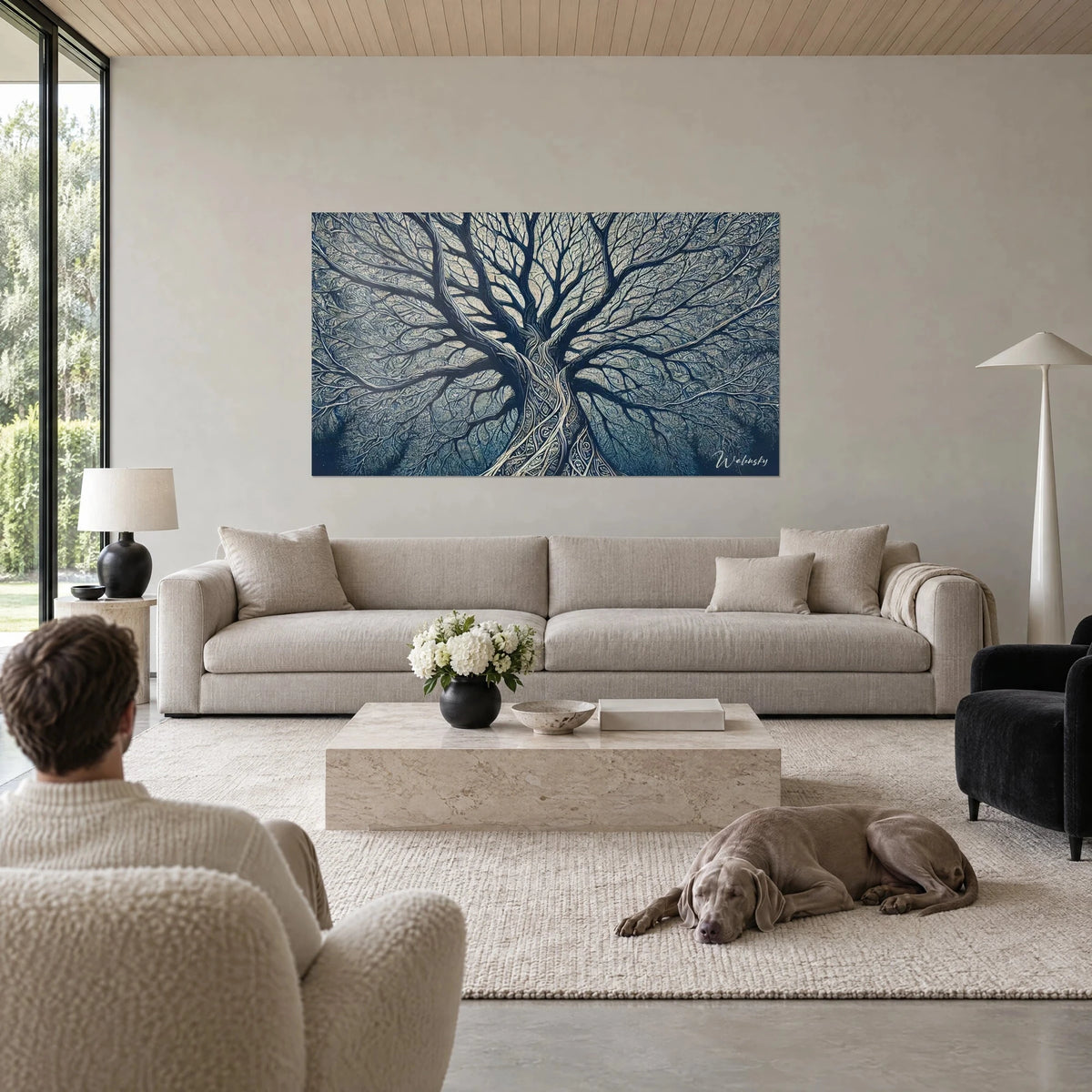 Gemälde eines riesigen Baums mit ineinander verschlungenen mitternachtsblauen Ästen auf sandfarbenem Grund, ein liegender Weimaraner, über einem Sofa in einem hellen Wohnzimmer