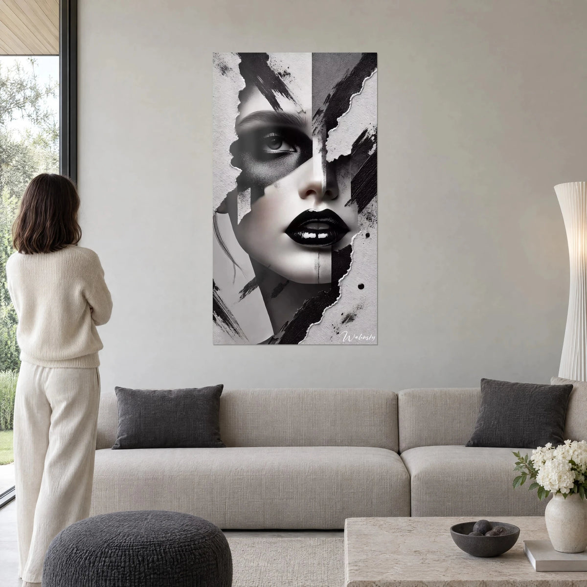Wall art woman's face with glossy black lacquered lips, torn grey and white paper, woman seen from behind above a sofa in a bright living room