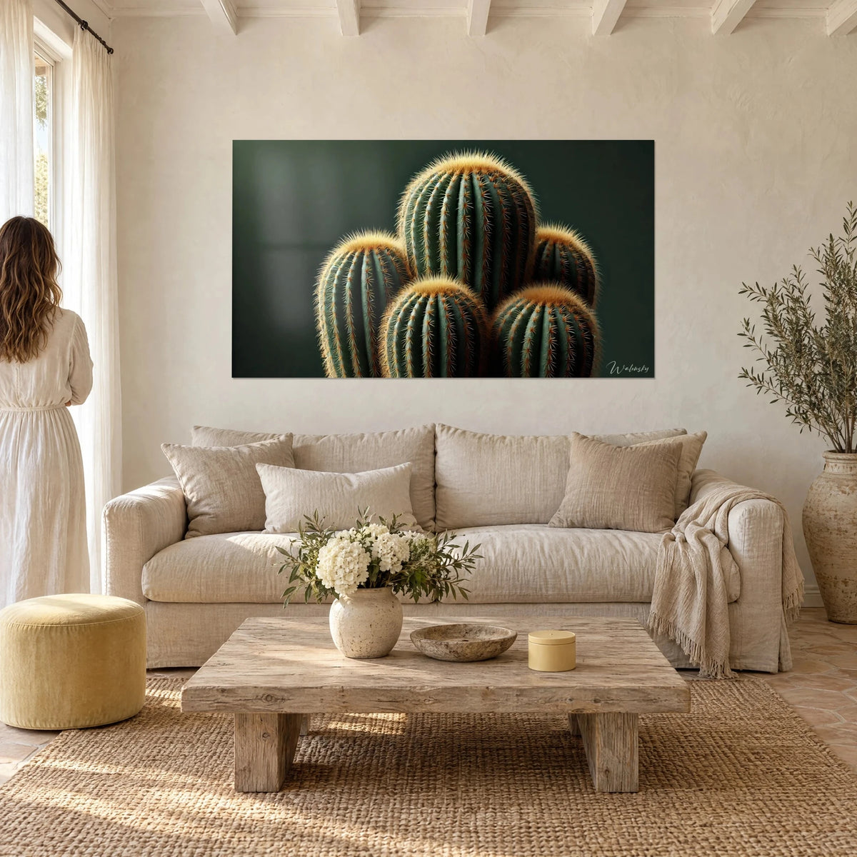 Quadro cactus a palla con spine dorate su sfondo verde scuro, donna di spalle, sopra un divano in un soggiorno luminoso