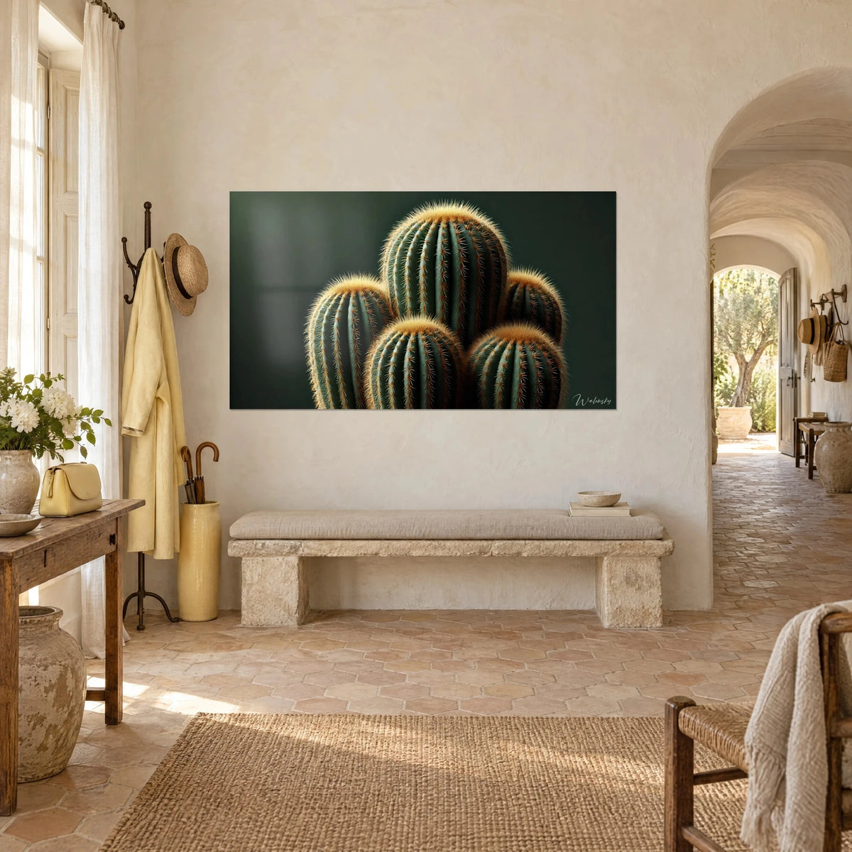 Quadro gruppo di cactus globulari costolati, verde profondo e ocra, appeso a una parete color crema di fronte a un arco in pietra