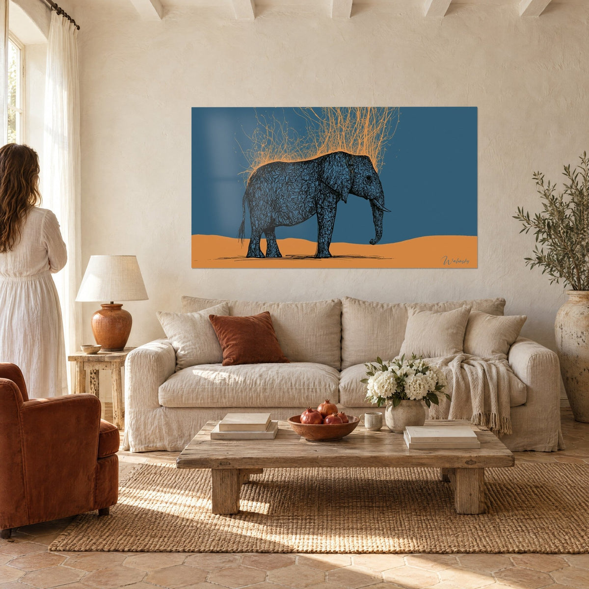 Cuadro paquidermo azul marino con motivos entrelazados, melena de raíces ocres doradas, duna anaranjada, encima de un sofá en un salón luminoso