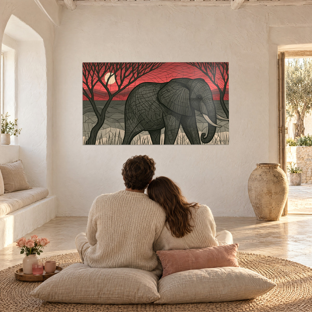 Quadro sagoma massiccia di elefante in nero e grigio, rami scuri e cielo rosso vivo, di fronte a una coppia di spalle su cuscini