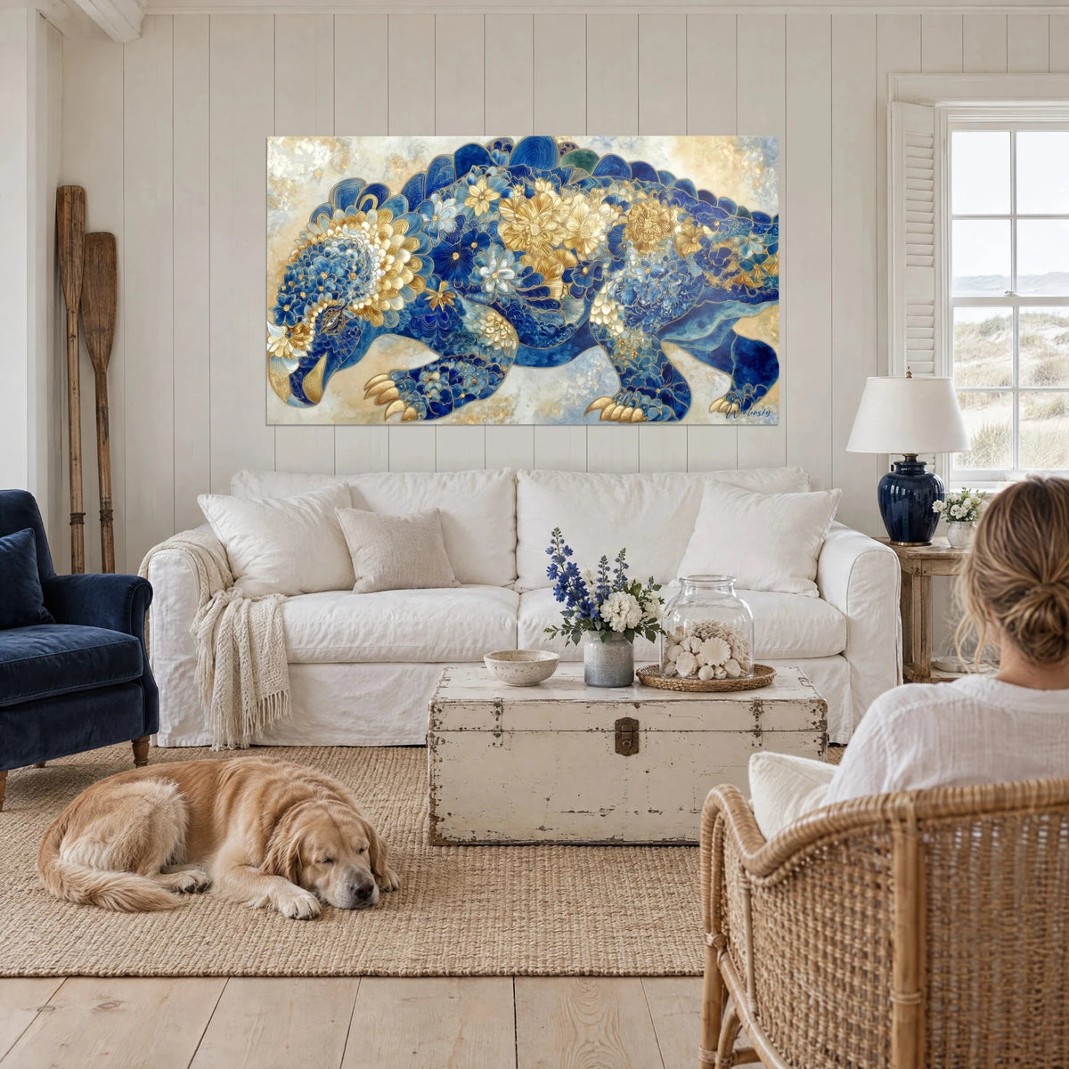 Cuadro Scutosaurus cubierto de flores doradas sobre fondo azul cobalto, personas de espaldas y un retriever, encima de un sofá en un salón luminoso