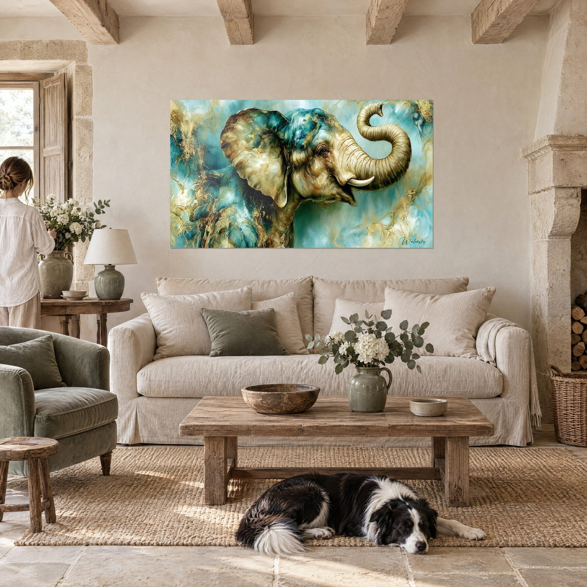 Quadro di elefante con la proboscide arrotolata, turchese e oro, di fronte a due visitatori, collie sdraiato, sopra un divano in un soggiorno luminoso