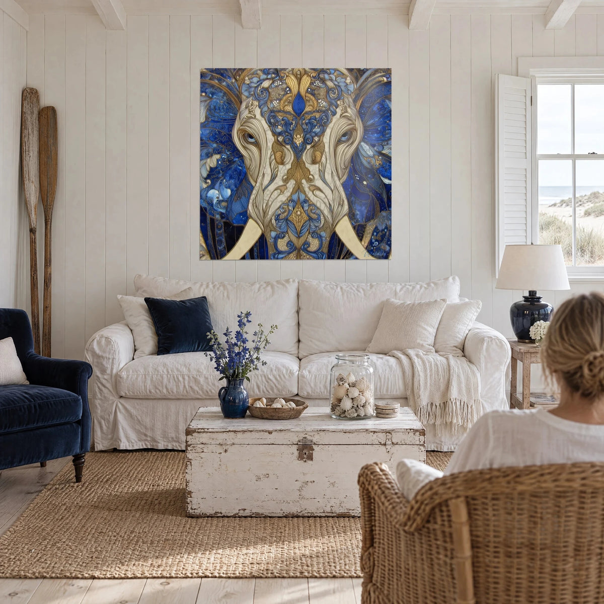 Gemälde Ornamentaler Elefant mit elfenbeinfarbenen Stoßzähnen, kobaltblaue und goldene Voluten, über einem Sofa in einem hellen Wohnzimmer