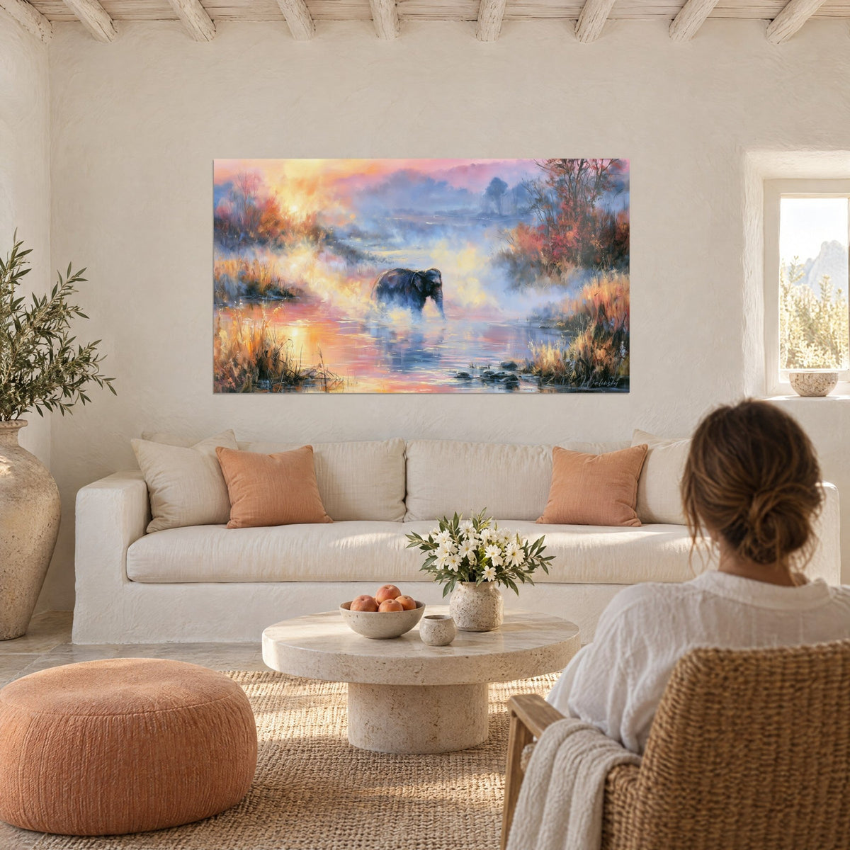 Wall art grey elephant wading through pink and golden mist, red bushes on the right, above a sofa in a bright living room