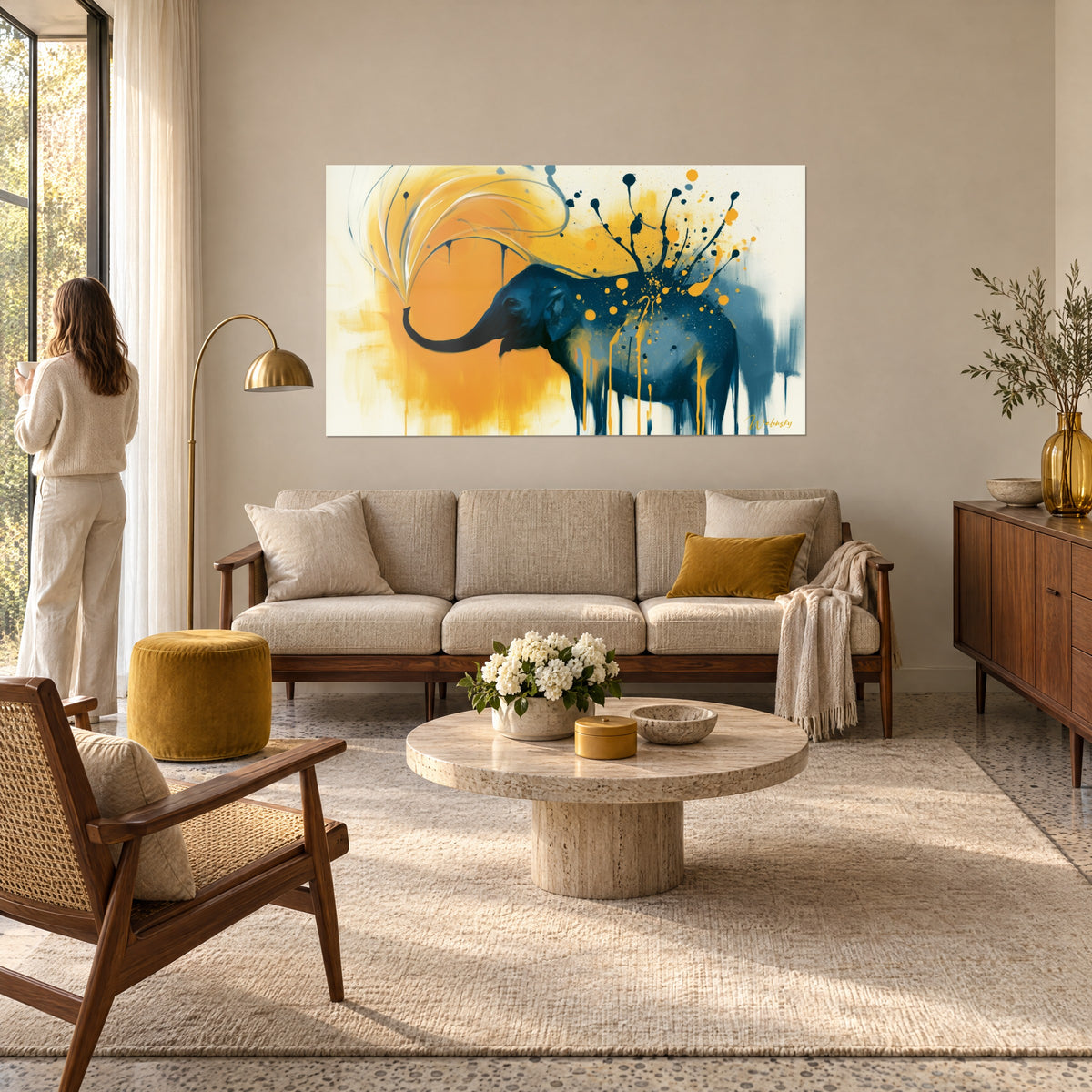 Gemälde Elefant in Marineblau, den Rüssel zu einem ockerfarbenen Lichthof erhoben, schwarze Spritzer, eine Frau von hinten, über einem Sofa in einem hellen Wohnzimmer