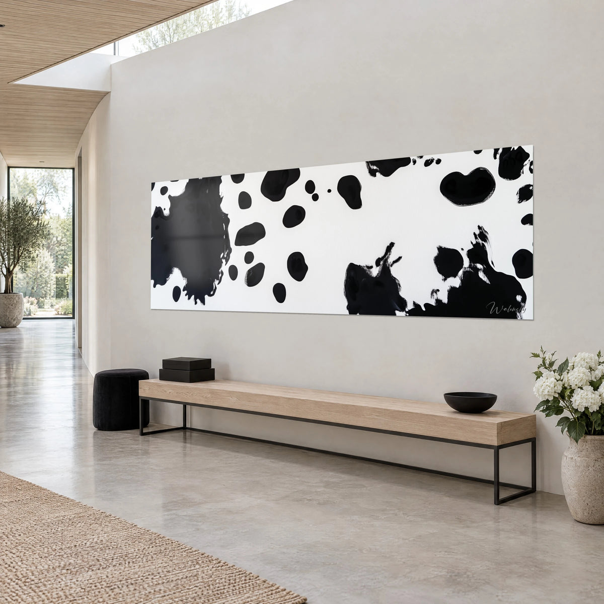 Panoramisch schilderij met gevlekt koeienhuid-effect, diepzwart op wit, opgehangen boven een bank van licht hout