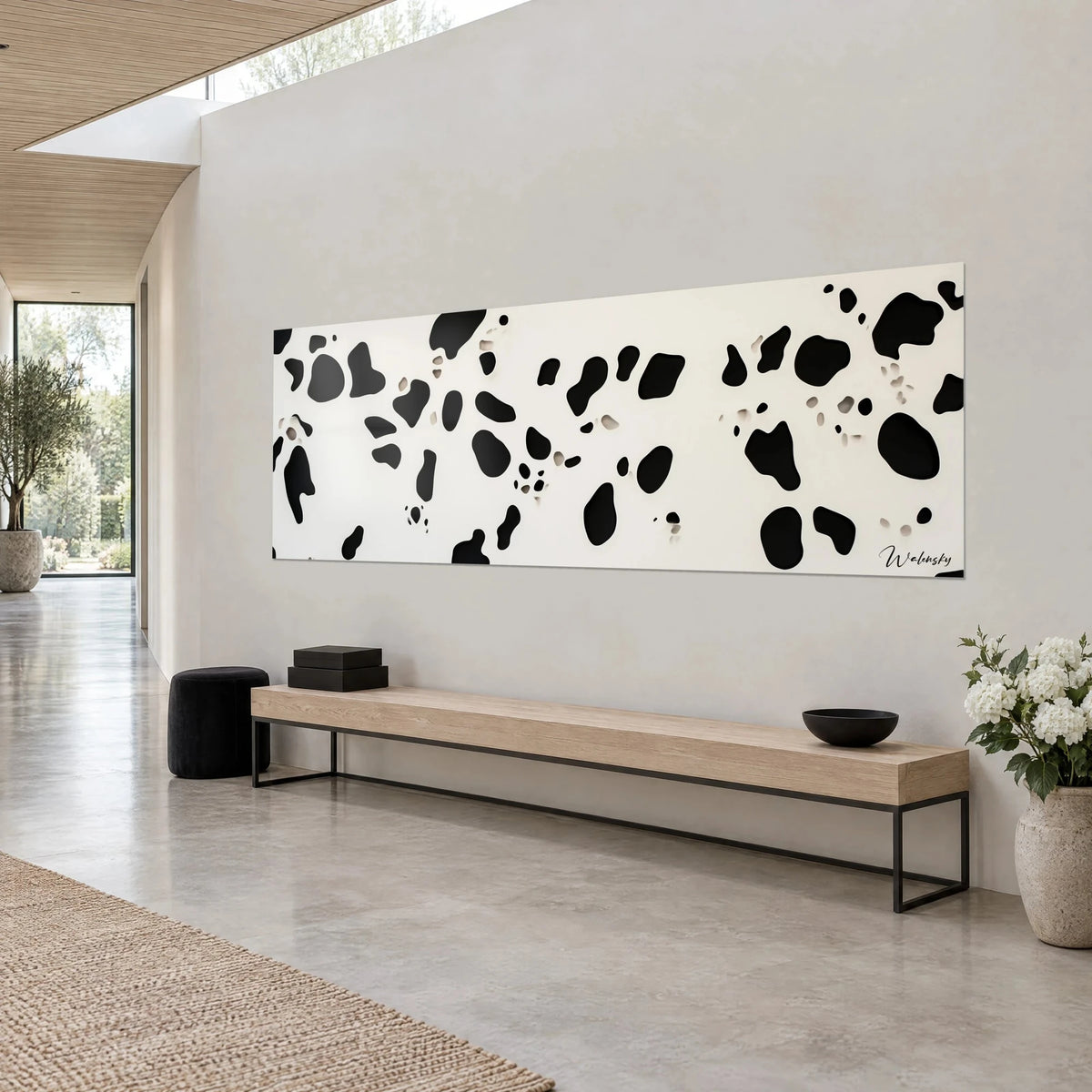 Tableau taches noires organiques sur fond blanc crème, format panoramique en vue de trois-quarts, banc en bois clair et sol en béton gris