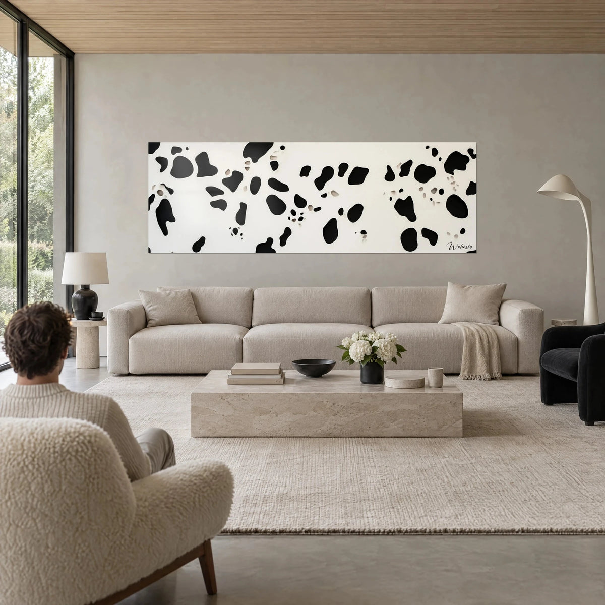 Tableau motif tacheté façon pelage de vache, taches noires sur fond ivoire, accroché dans un salon, au-dessus d'un canapé dans un salon lumineux