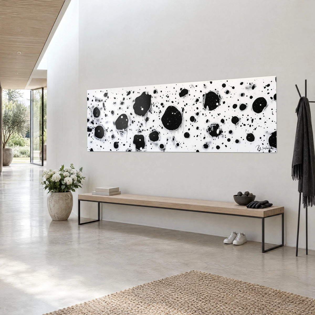 Cuadro panorámico de manchas negras moteadas sobre blanco brillante, visto de tres cuartos, en un salón claro con acabado de hormigón pulido