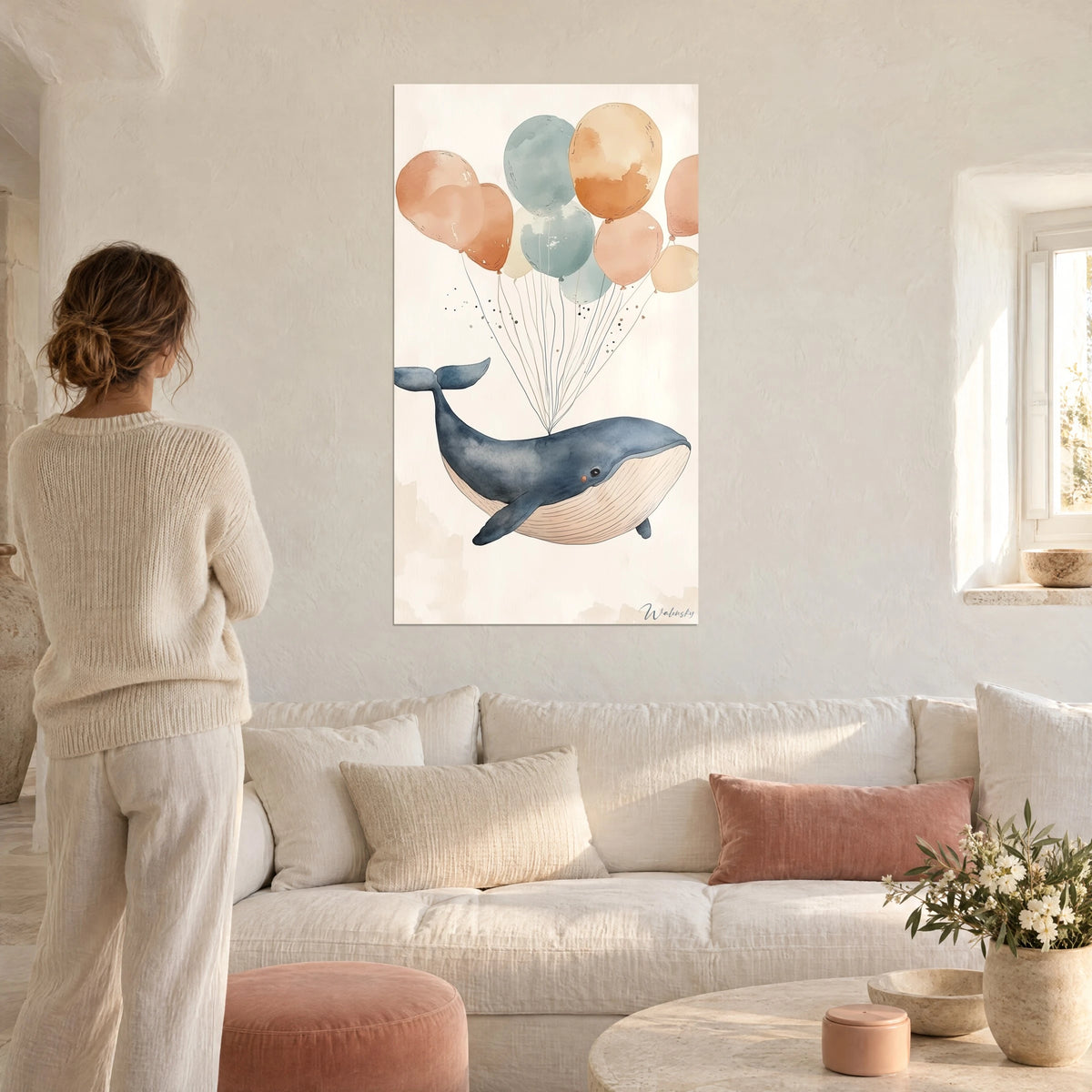 Gemälde mit einem schiefergrauen Wal, getragen von ockerfarbenen und graugrünen Ballons, Frau von hinten, über einem Sofa in einem hellen Wohnzimmer