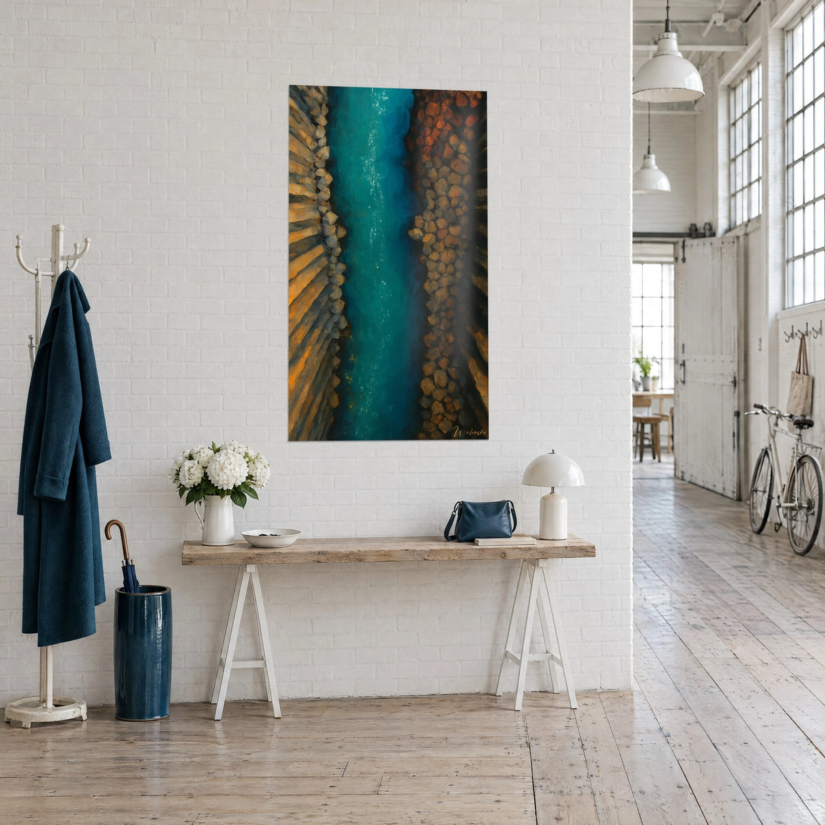 Tableau canal d'eau bleu-vert vu d'en haut, galets orange et sable doré, sur un mur blanc de loft d'artiste