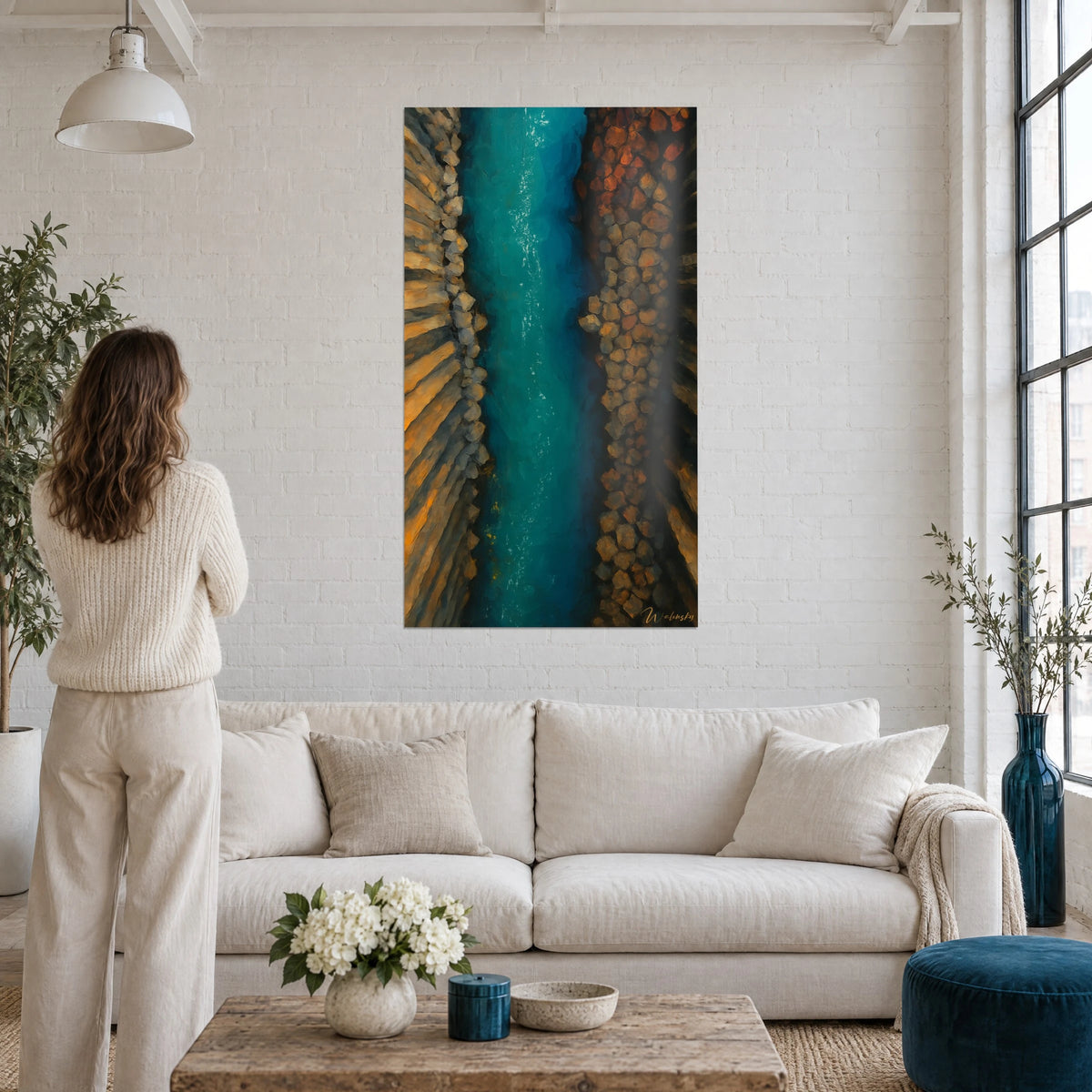 Tableau rivière turquoise entre colonnes de basalte ocre, femme de dos, au-dessus d'un canapé dans un salon lumineux