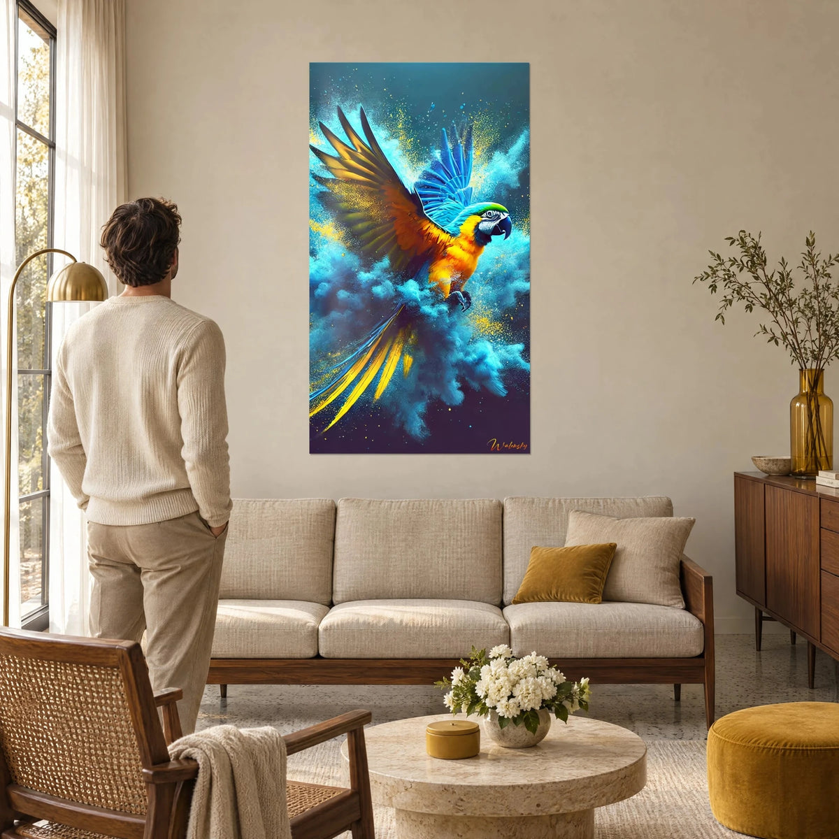 Tableau ara bleu et jaune en plein vol, ailes orange ouvertes dans un nuage turquoise, homme de dos, au-dessus d'un canapé dans un salon lumineux