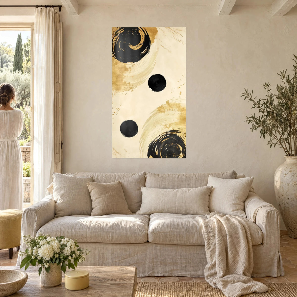 Tableau spirales de pinceau noir et or sur fond crème, trois cercles d'encre, femme de dos, au-dessus d'un canapé dans un salon lumineux
