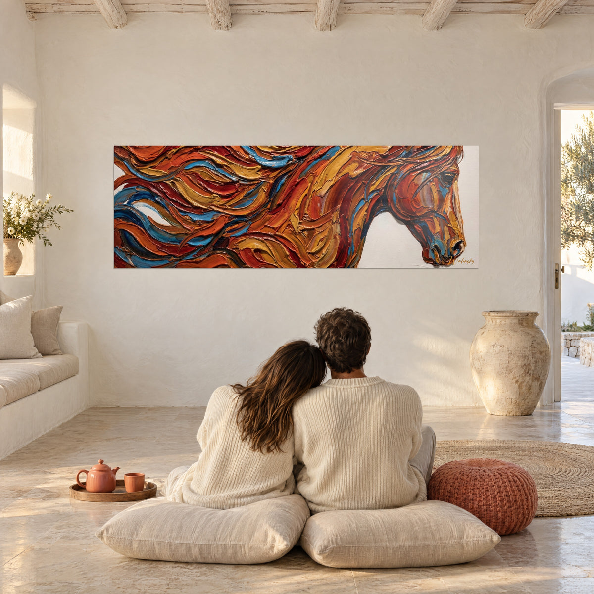 Cuadro cabalgada con crin arremolinada ocre, roja y azul, una pareja abrazada de espaldas sobre cojines en un gran salón blanco
