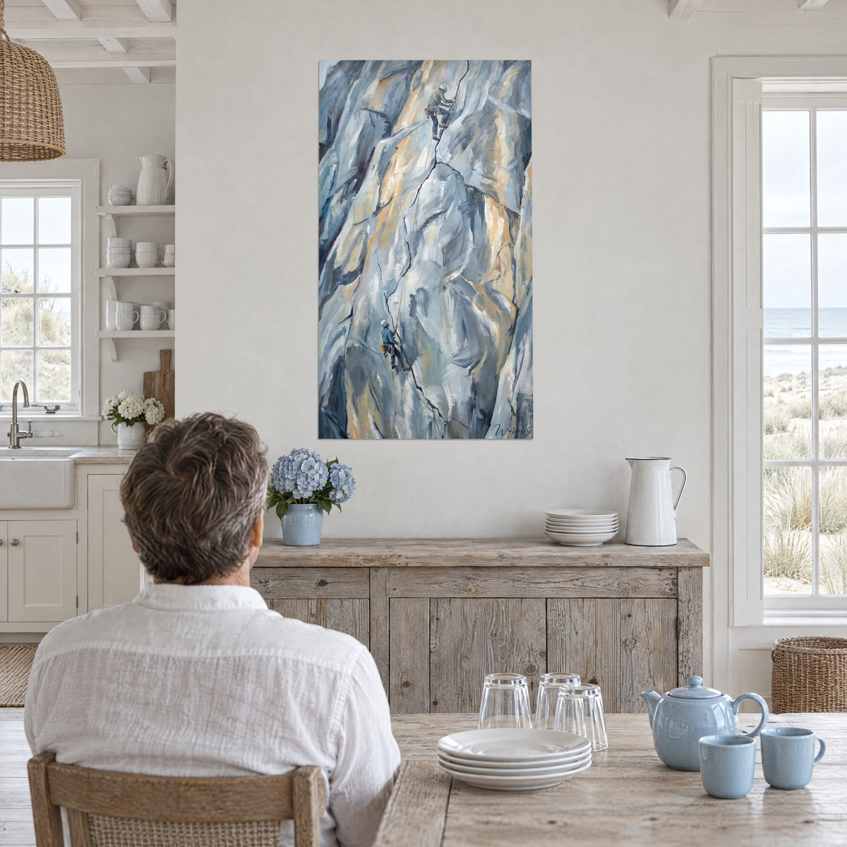 Quadro arrampicata dipinta a olio, scalatore con casco bianco su roccia grigio-azzurra e beige dorato, uomo di spalle a un tavolo, casa sul mare