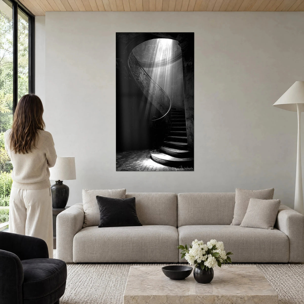 Wall art spiral staircase bathed in pearl-grey light beams, black wrought-iron railing, above a sofa in a bright living room