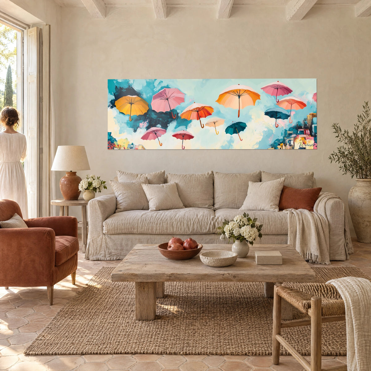 Wall art of floating orange and pink umbrellas against a turquoise sky, two people seen from behind above a sofa in a bright living room