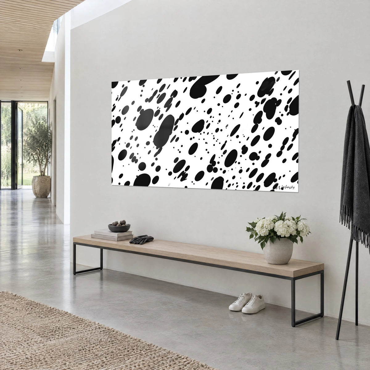 Tableau pelage tacheté noir et blanc, grandes ovales d'encre et fins points, accroché au mur gris au-dessus d'un banc en bois