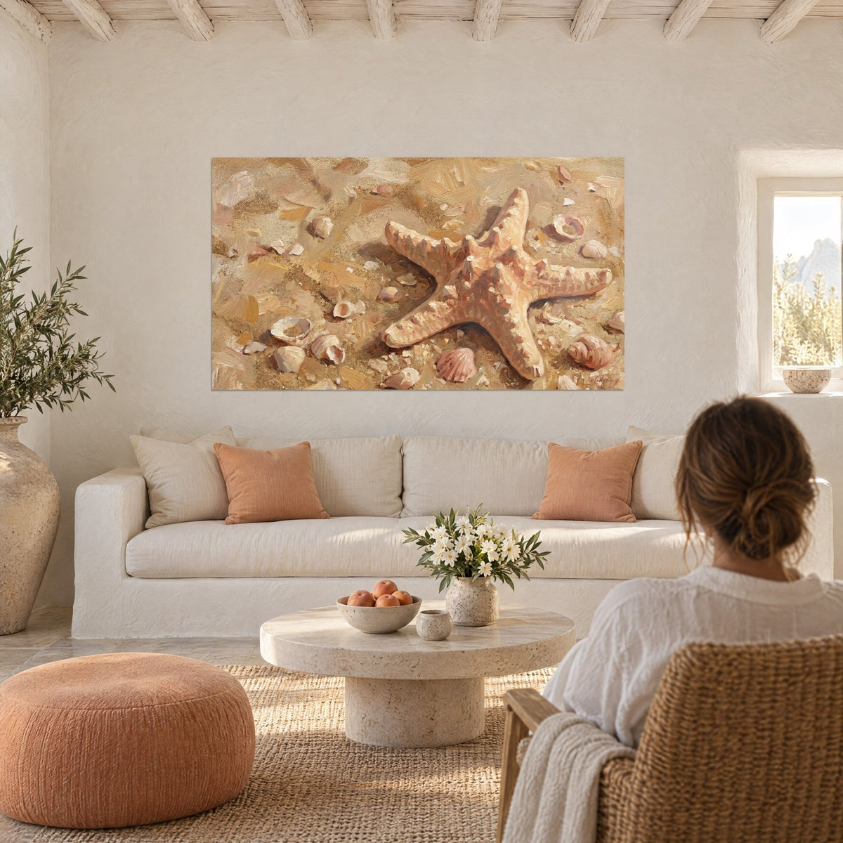 Gemälde Seestern in Lachsrosa auf ockerfarbenem, mit Muscheln übersätem Sand, über einem Sofa in einem hellen Wohnzimmer