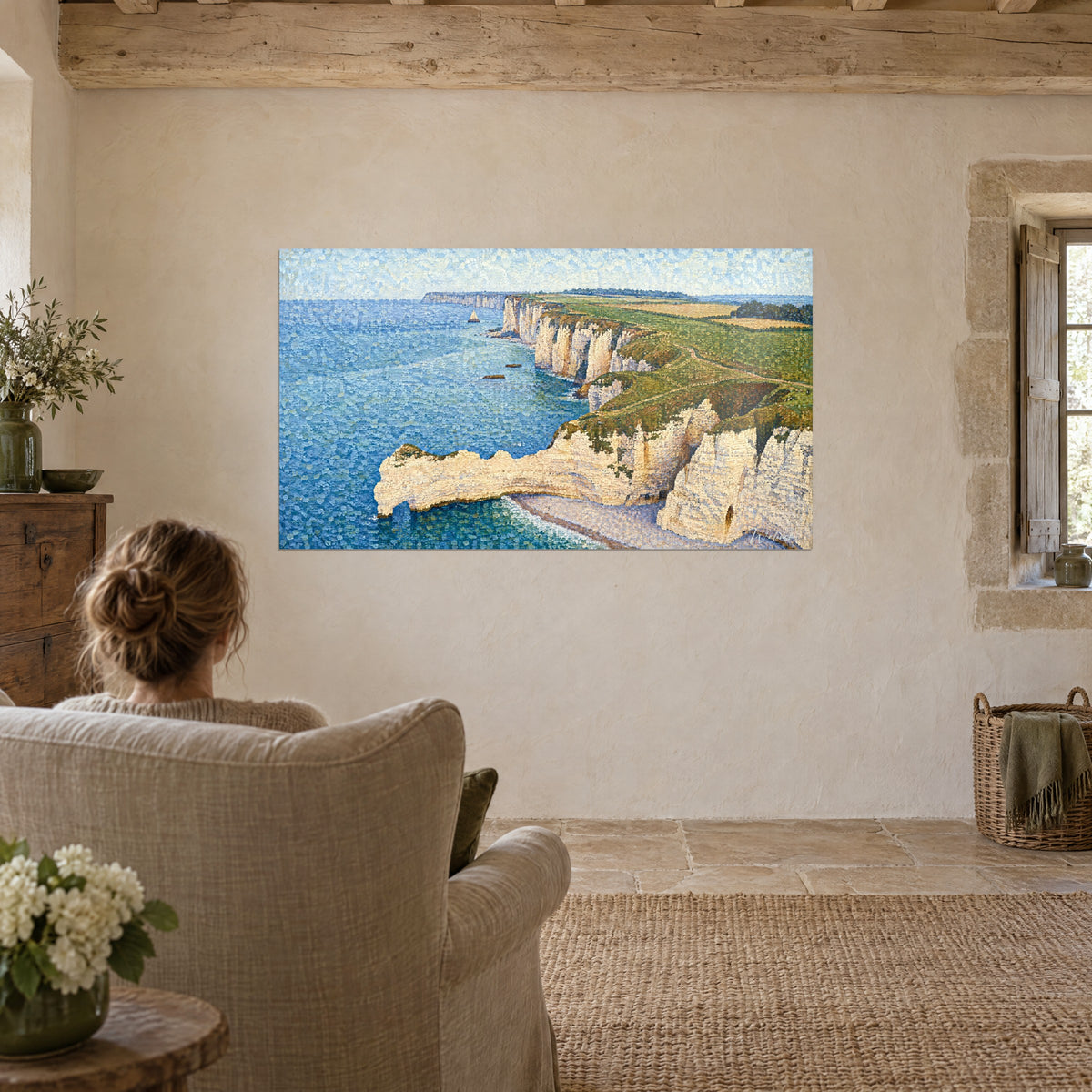 Schilderij bovenaanzicht op een krijtboog, gespikkelde blauwe zee en gele velden, vrouw van achteren zittend in een linnen fauteuil