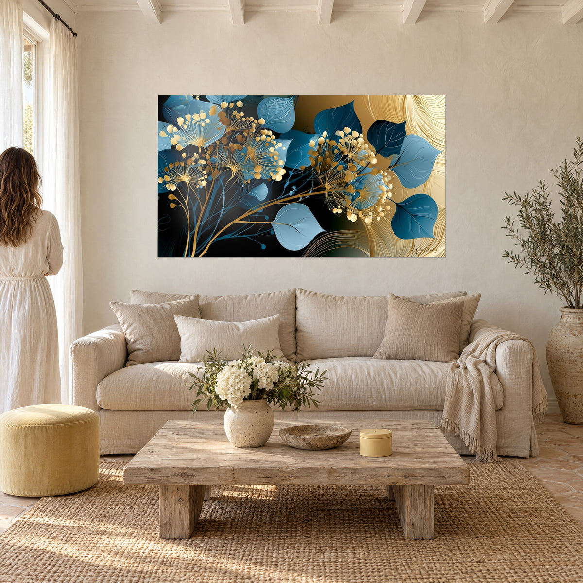 Tableau fleurs d'or filigranées sur feuilles bleu pétrole et fond noir, une femme de dos, au-dessus d'un canapé dans un salon lumineux