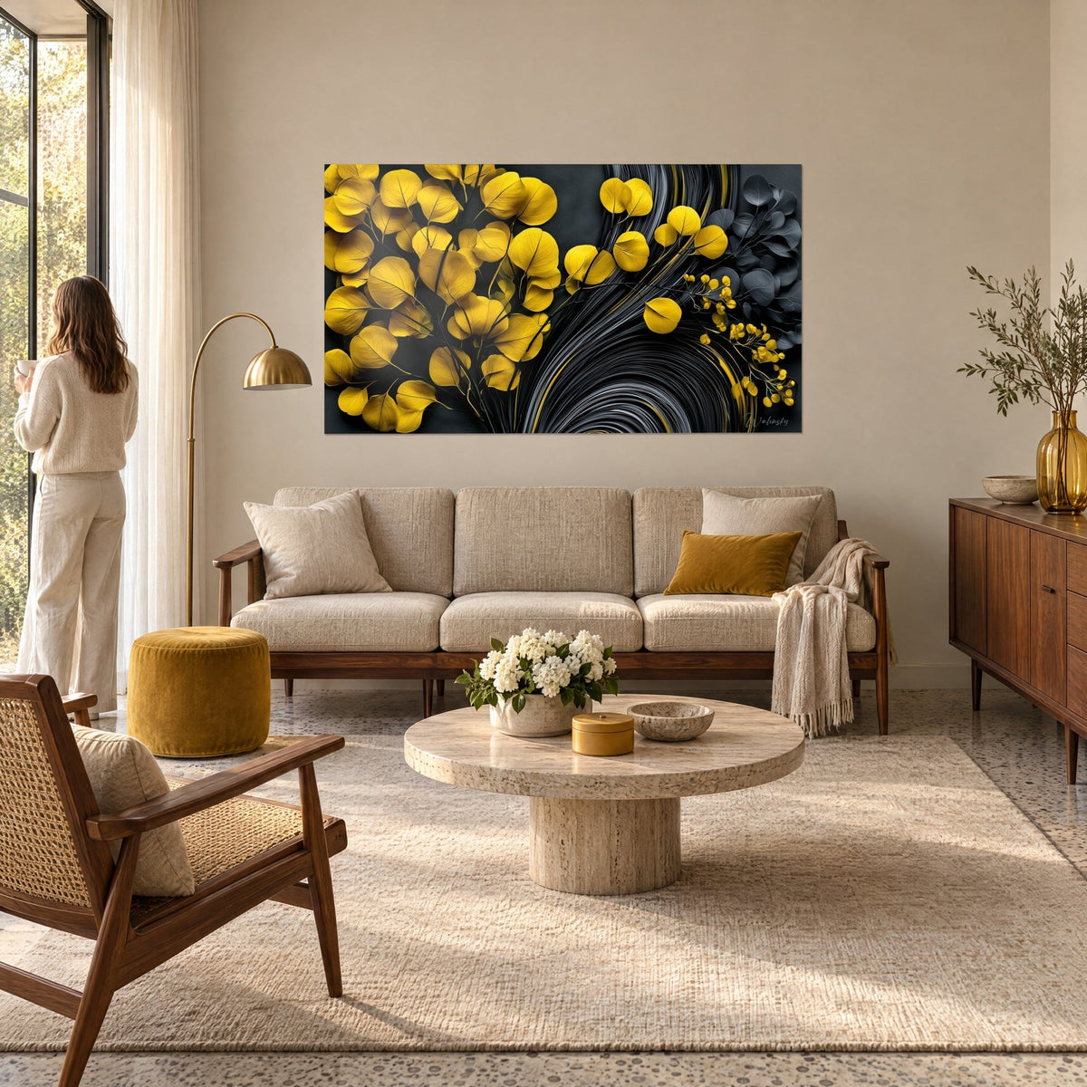 Wall art mustard yellow eucalyptus leaves on charcoal background, silver spiral, woman seen from behind, above a sofa in a bright living room