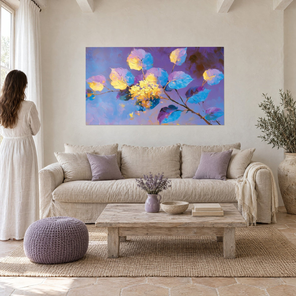 Gemälde mit violettem Eukalyptuszweig, blauen und goldenen Blättern, Frau von hinten, über einem Sofa in einem hellen Wohnzimmer