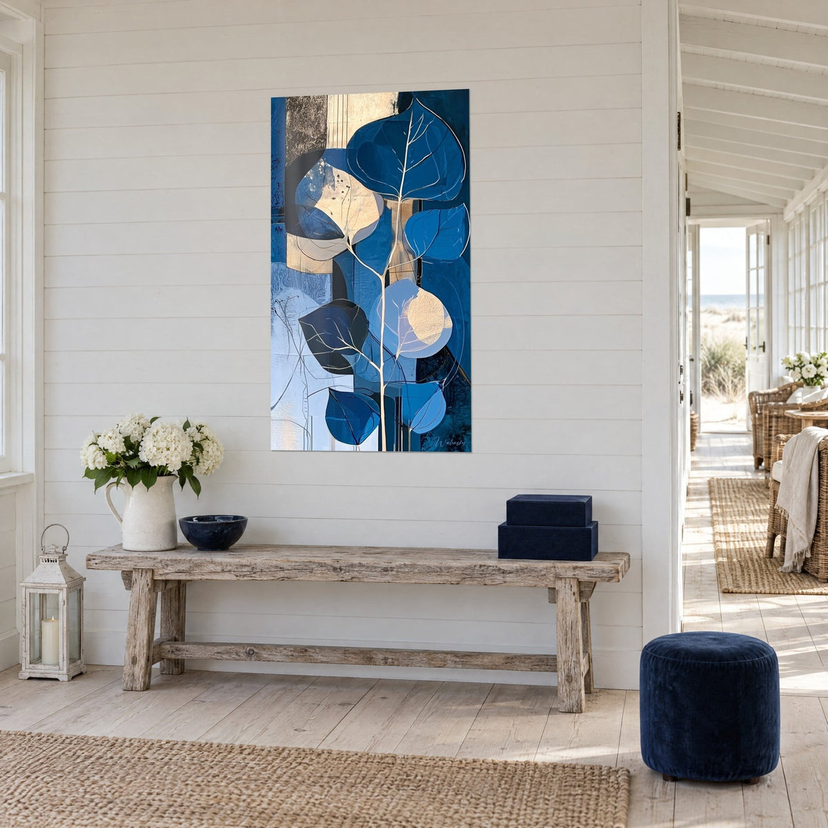 Quadro ramo di eucalipto con nervature dorate, blu reale e beige sabbia, di fronte a una consolle in legno in una casa sul mare